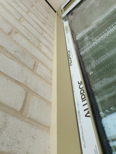 Aluminium window frame in a buff brick reveal, ready for perimeter sealing