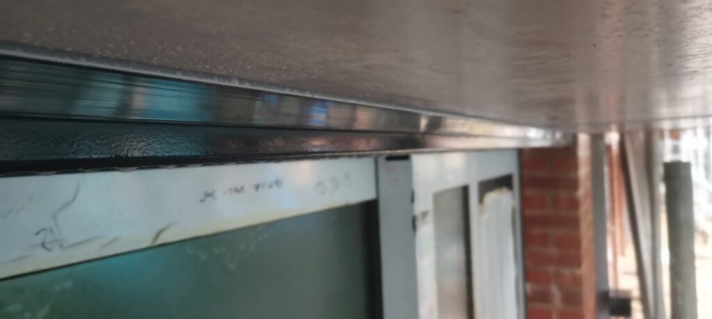 Sealed joint between an aluminium window head and a dark soffit