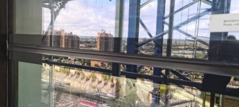 Curtain wall glazing transom on a high-rise, city view behind