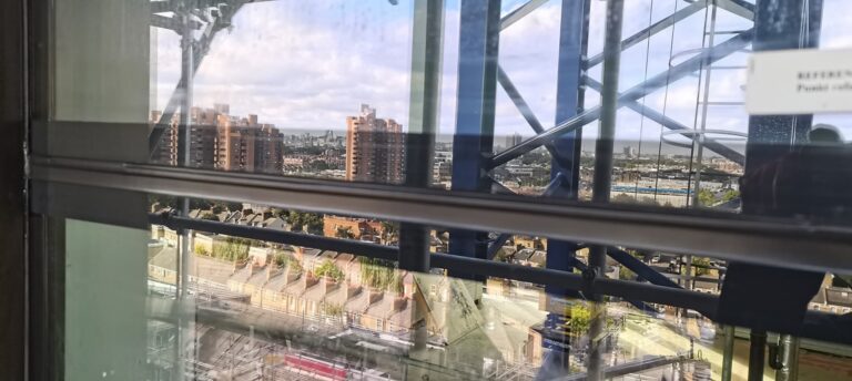 Curtain wall glazing transom on a high-rise, city view behind