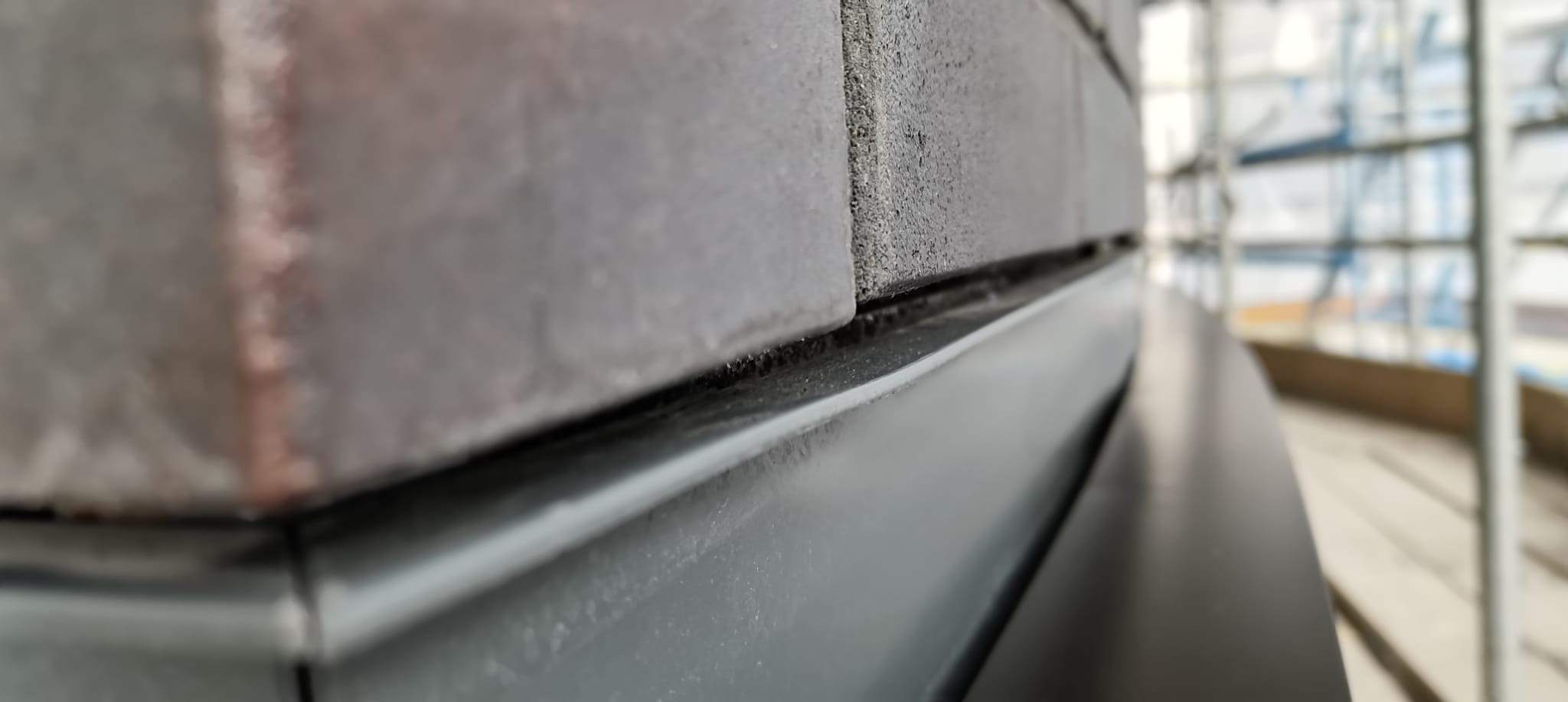 Sealant joint between dark brick and a grey metal flashing