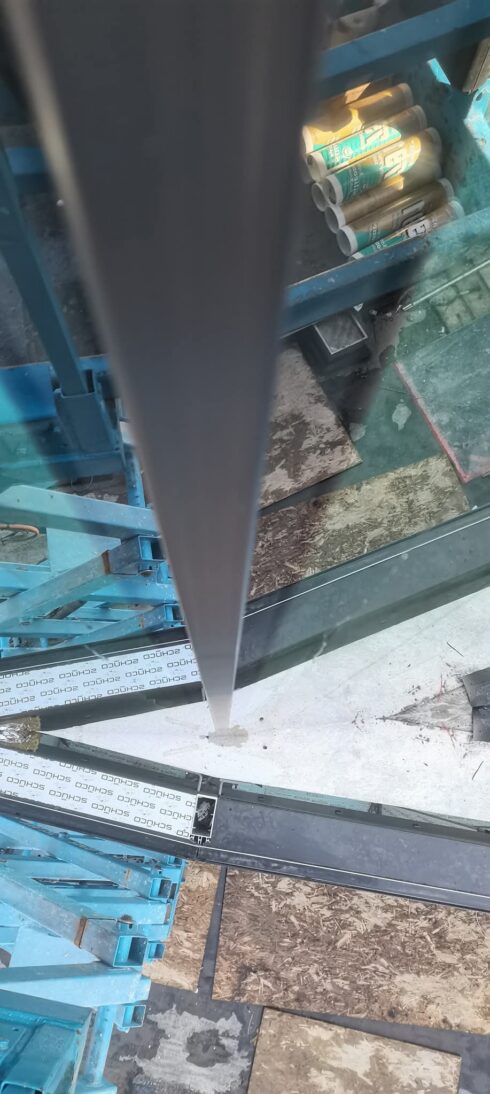 Dark grey metal cladding fin viewed from above, scaffold below