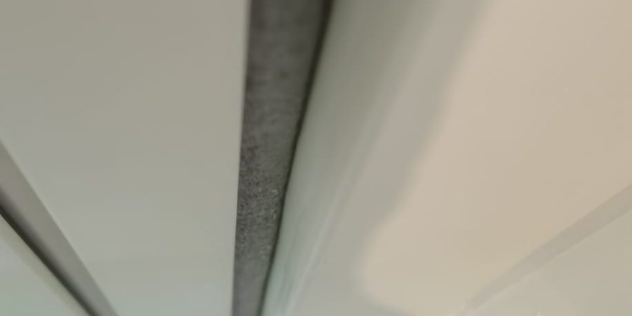 Long grey sealant joint along white wall panels, seen from below