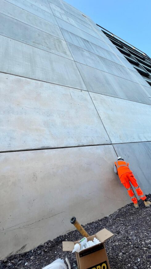 Applicator sealing joints between large precast concrete wall panels at a development in Dagenham, east London