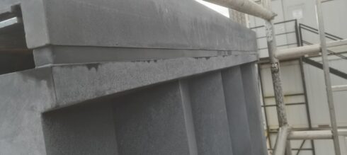 Grey sealant joint beneath a stone coping on a column