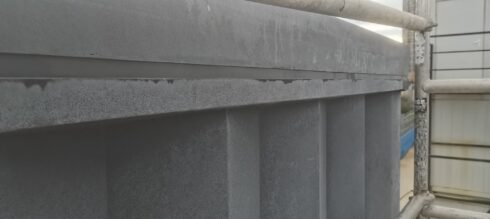 Grey sealant joint under a stone coping on fluted columns
