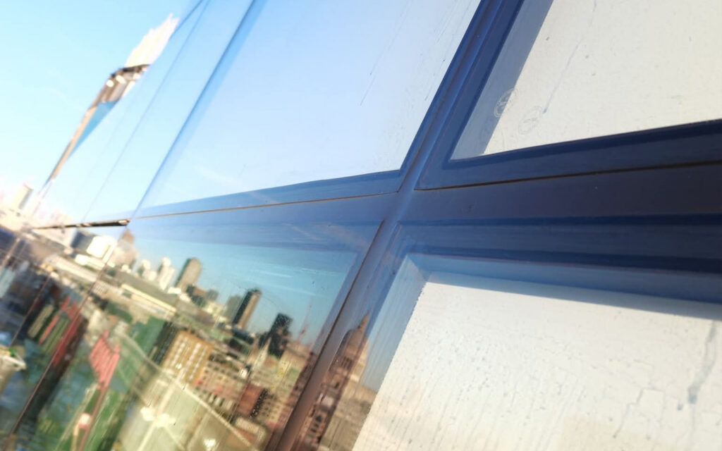 Curtain wall glazing with dark grey framing reflecting a city skyline