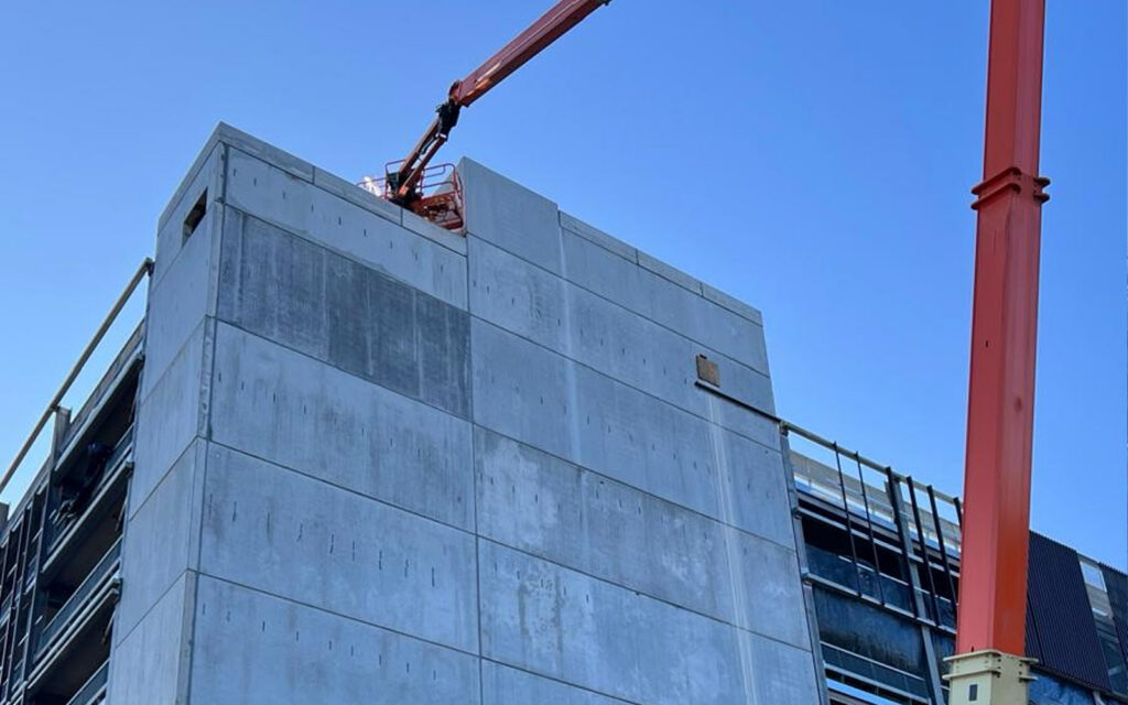 Boom lift beside a precast concrete stair core for high-level joint sealing