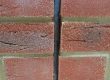 Vertical movement joint in red brickwork sealed with dark grey sealant