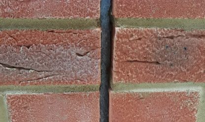 Vertical movement joint in red brickwork sealed with dark grey sealant