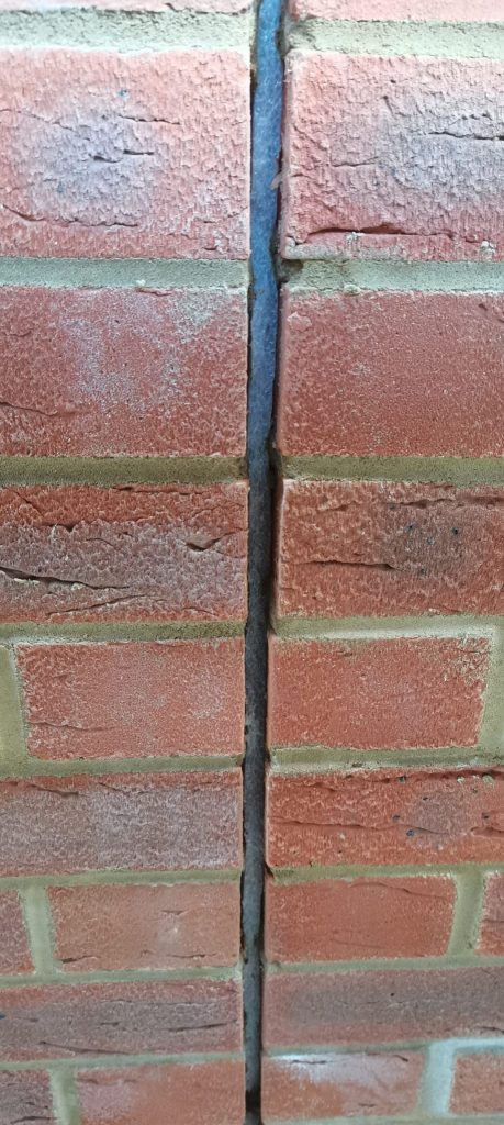 Vertical movement joint in red brickwork sealed with dark grey sealant